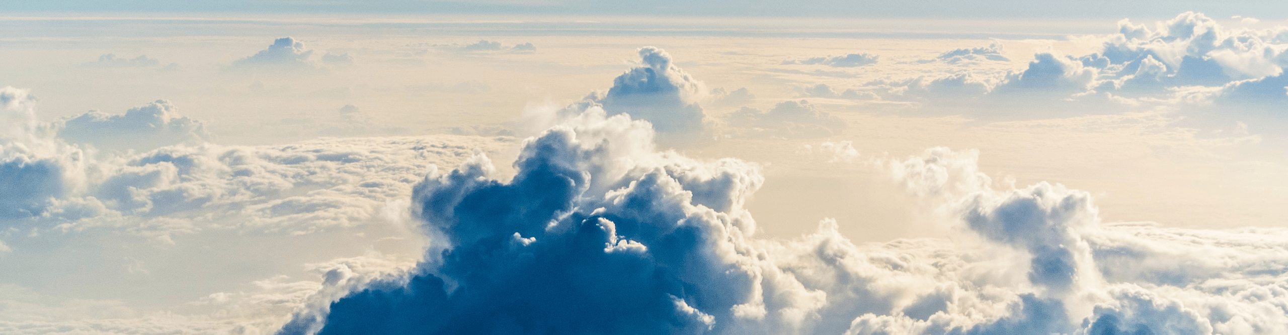 Blick auf die Wolken eines Tiefdruckgebietes aus der Flugzeugperspektive, mit Sonnenschein, der durch die Wolken scheint. 
