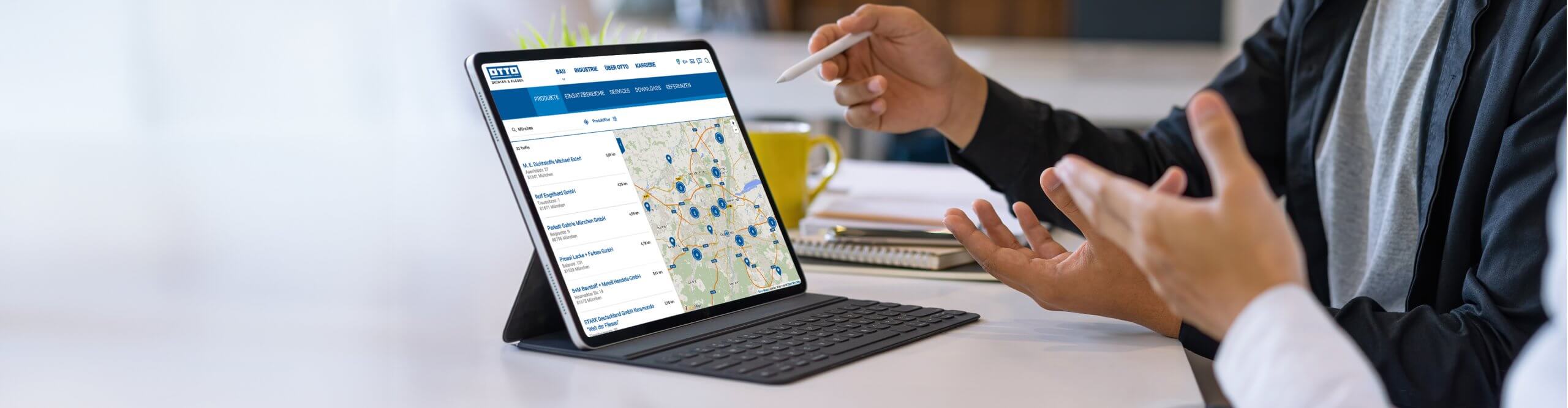 Zwei Personen sprechen miteinander und betrachten auf einem Tablet die Fachhändlersuche des Unternehmens Otto Chemie, die mit SmartMaps umgesetzt wurde.