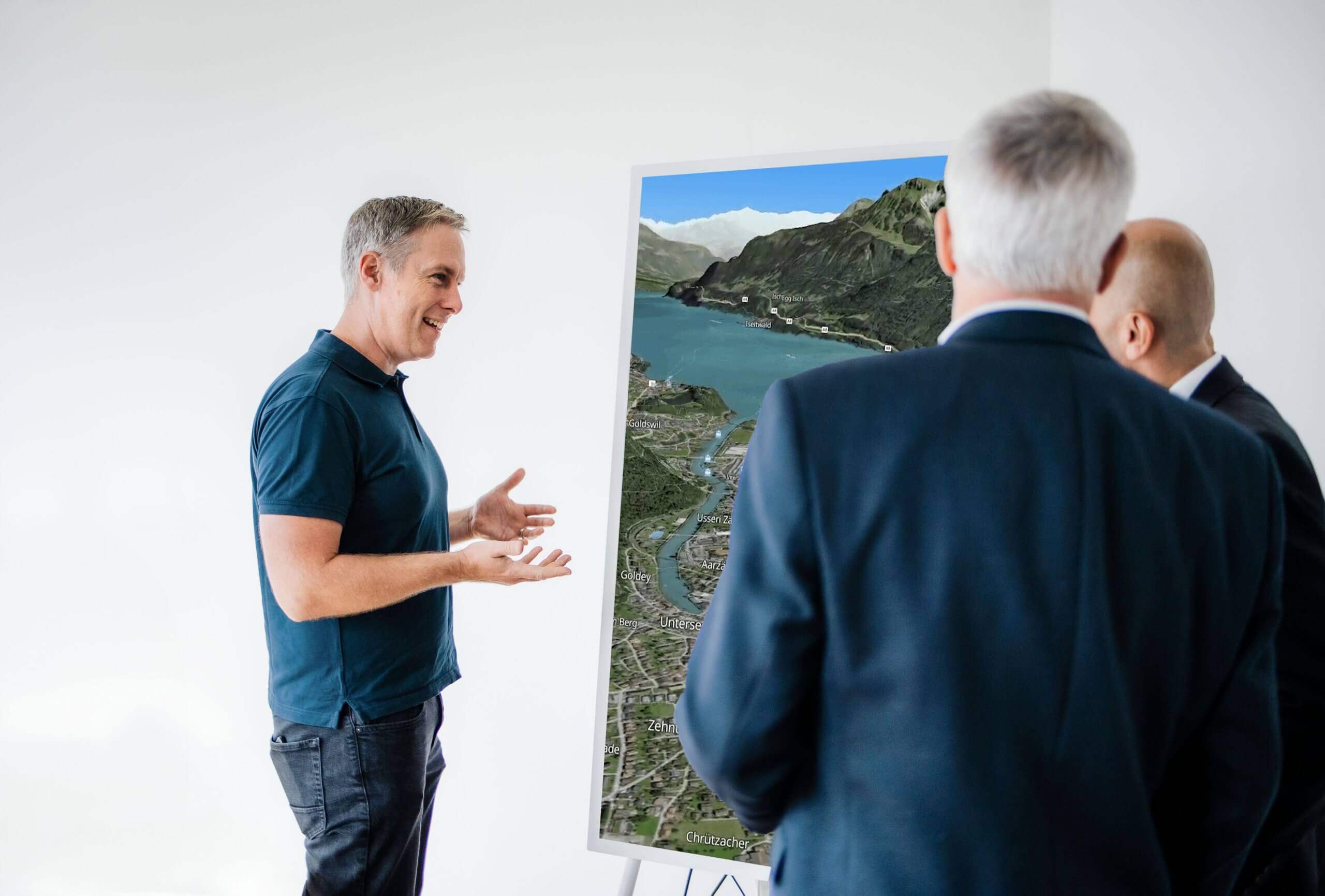 Mehrere Personen stehen vor einem Bildschirm und tauschen sich über eine SmartMaps Kartenanwendung aus.